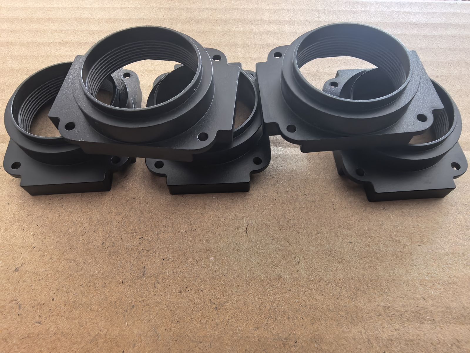 Four black anodized aluminum sensor housings in a tray
